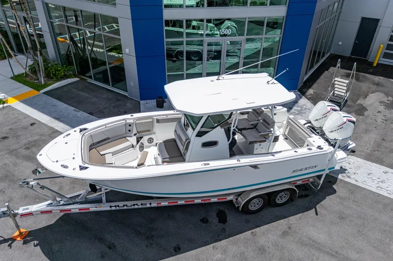 Slide: The Image of 2019 Blackfin 272 CC boat on trailer outside dealership, featuring dual engines. - 6