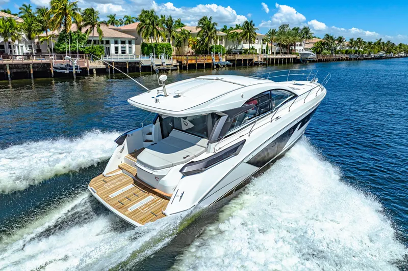 Slide: The Image of 2024 Beneteau Gran Turismo 45 yacht cruising on a sunny waterfront with palm trees. - 25