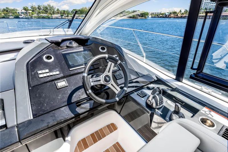 Slide: The Image of 2024 Beneteau Gran Turismo 45 helm with modern controls and scenic water view. - 55