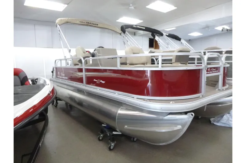 The Image of 2025 Sun Tracker Bass Buggy 18 DLX pontoon boat in showroom, red and silver design. - 1