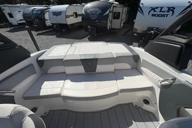 Slide: The Image of 2020 Chaparral 21 SSi boat interior with white seating and nearby RVs. - 15