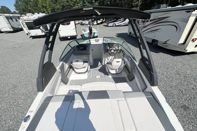 Slide: The Image of 2020 Chaparral 21 SSi boat interior with seating and steering wheel, parked among RVs. - 18