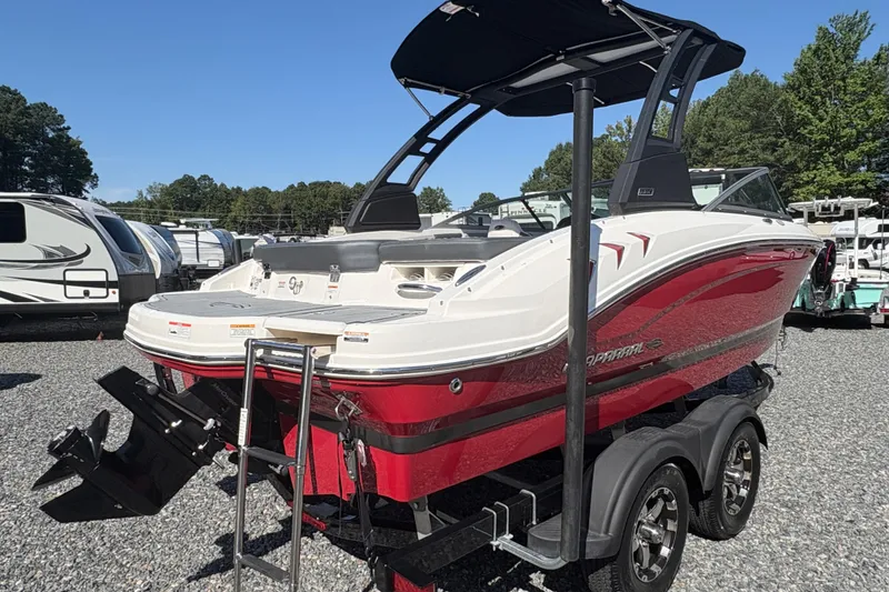 Slide: The Image of 2020 Chaparral 21 SSi boat in red and white on a trailer, parked outdoors. - 19
