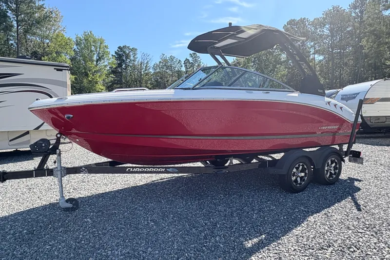 Slide: The Image of 2020 Chaparral 21 SSi boat in vibrant red on a trailer, parked outdoors. - 2