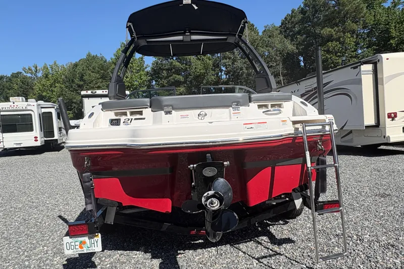 Slide: The Image of 2020 Chaparral 21 SSi boat, red and white, parked outdoors with RVs in background. - 3