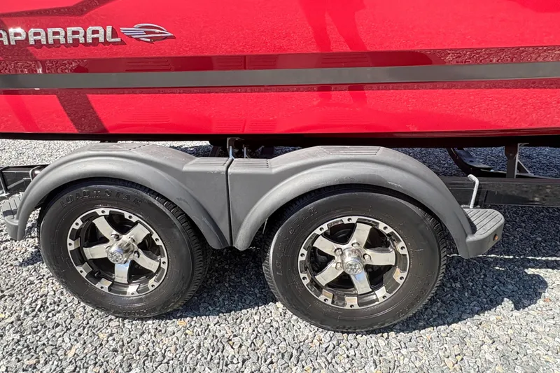Slide: The Image of 2020 Chaparral 21 SSi boat trailer with dual wheels on gravel surface. - 5
