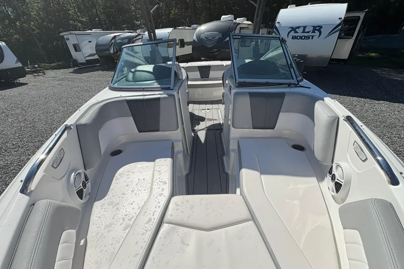 Slide: The Image of 2020 Chaparral 21 SSi boat interior with seating and speakers, parked near RVs. - 6