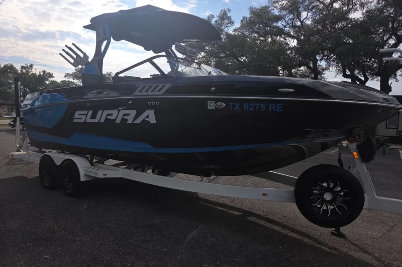 Slide: The Image of 2021 Supra SE 450 boat on trailer, black and blue design, parked outdoors. - 3