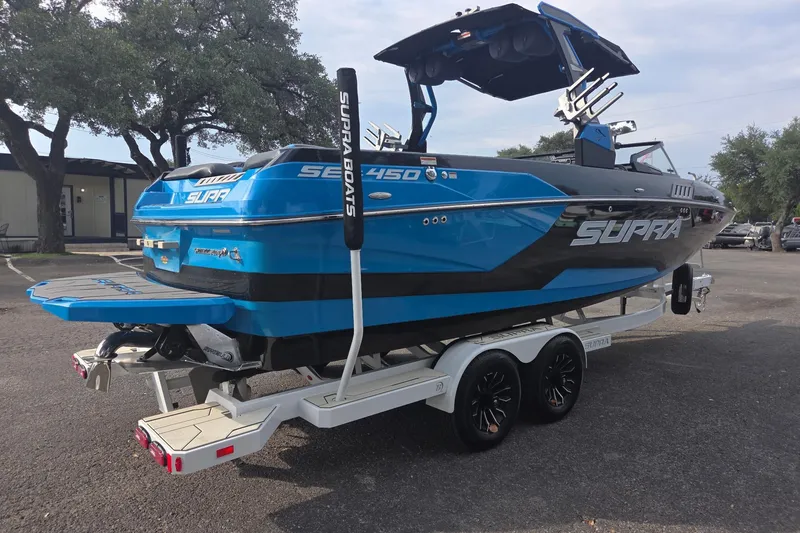 Slide: The Image of 2021 Supra SE 450 boat in blue on a trailer, parked outdoors. - 4