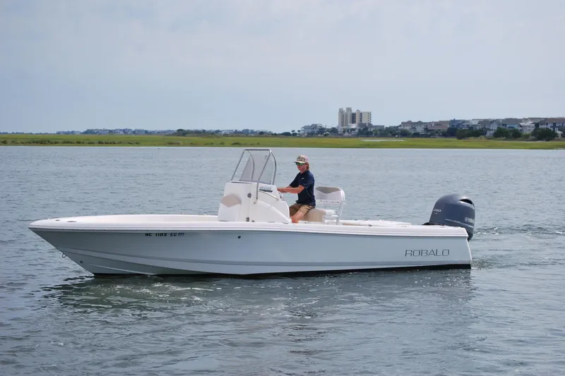 The Image of 2016 Robalo 226 Cayman boat cruising on calm water with a person at the helm. - 0