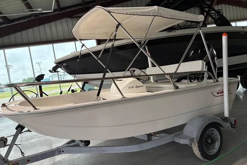 Slide: The Image of 2017 Boston Whaler 110 Sport boat with canopy on trailer in indoor storage. - 1