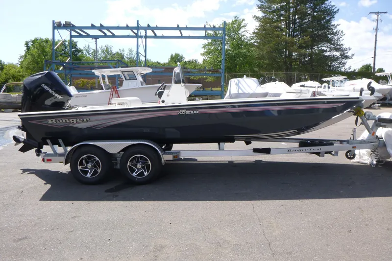 The Image of 2025 Ranger RB210 boat on trailer, parked outdoors with other boats in background. - 1