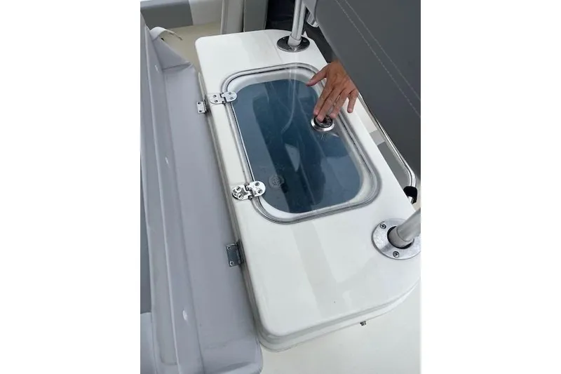 Slide: The Image of 2021 Mako 214 CC boat livewell with hand opening the lid. - 9
