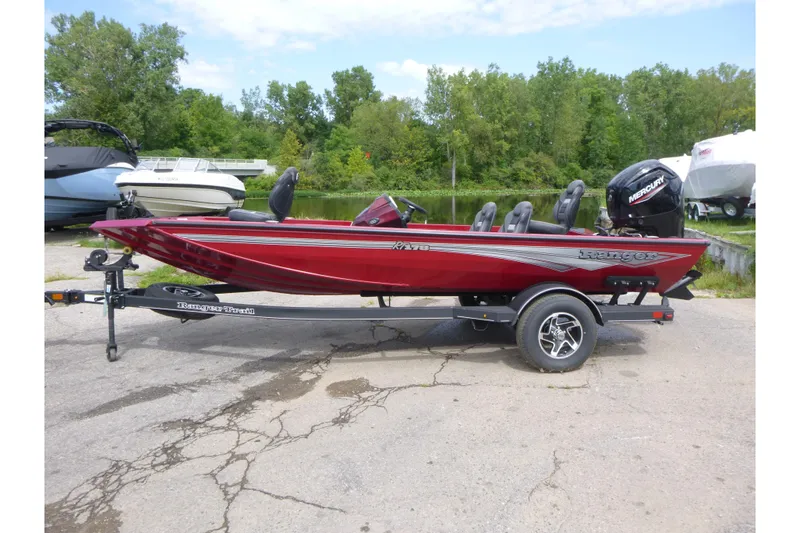 The Image of 2024 Ranger RT178 boat in red, parked on a trailer near a lake. - 1