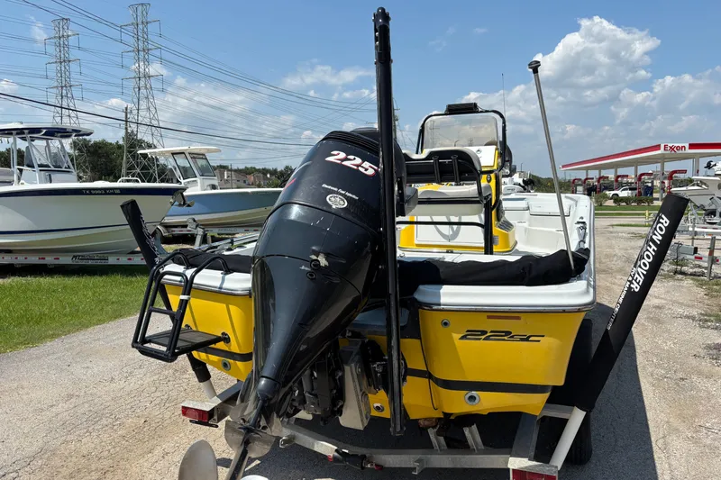 Slide: The Image of Yellow 2014 Epic 22 boat with outboard motor, parked near other boats and an Exxon station. - 6