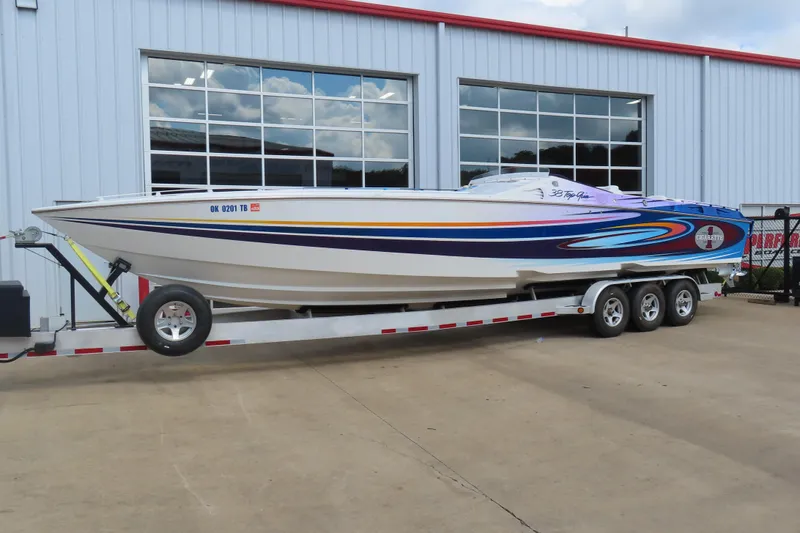 Slide: The Image of 2004 Cigarette 38 Top Gun TS speedboat on trailer, parked outside a garage. - 2