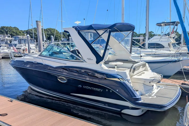 The Image of 2013 Monterey 280 Sport Yacht docked at marina, featuring sleek design and blue canopy. - 0