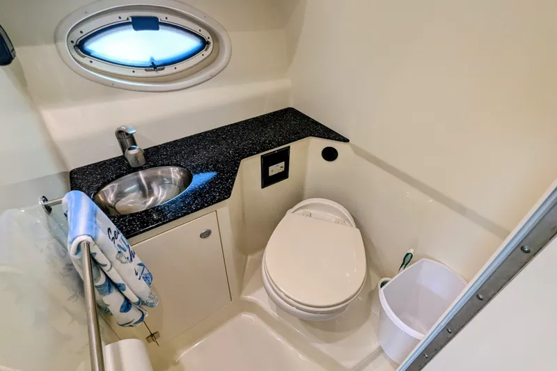 Slide: The Image of 2013 Monterey 280 Sport Yacht bathroom with sink, toilet, and porthole window. - 28