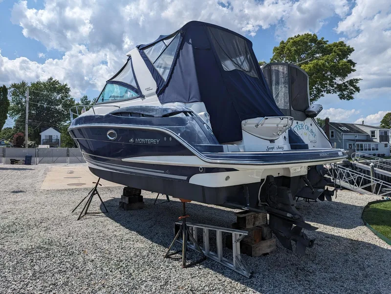 Slide: The Image of 2013 Monterey 280 Sport Yacht on dry dock, covered, with clear sky background. - 4