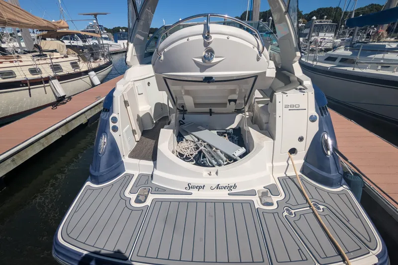 Slide: The Image of 2013 Monterey 280 Sport Yacht docked, open storage compartment, sleek design, marina background. - 6