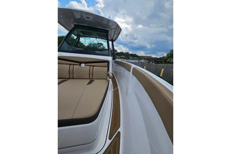 Slide: The Image of 2026 Monterey Elite 25 OB boat interior with tan seating and sleek design under a cloudy sky. - 22