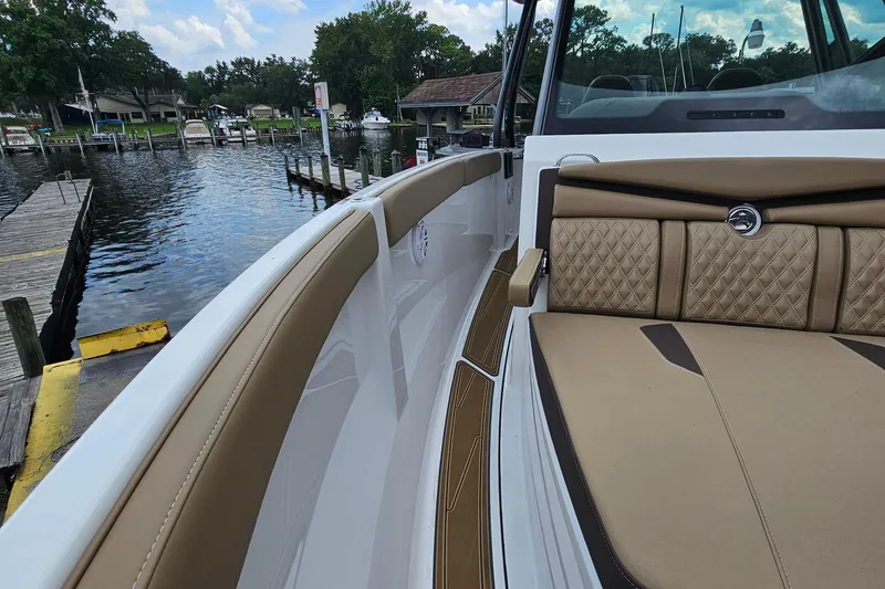 Slide: The Image of 2026 Monterey Elite 25 OB boat interior with tan seating, dockside view. - 23