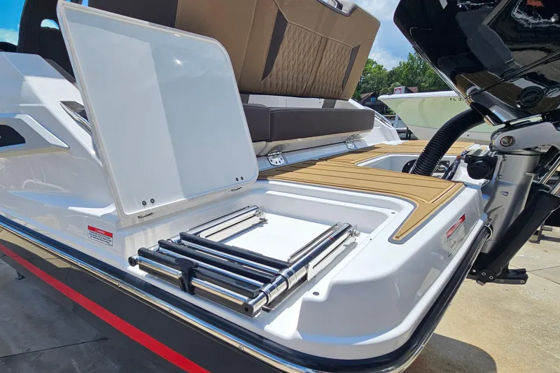Slide: The Image of 2026 Monterey Elite 25 OB boat with open storage compartment and ladder on deck. - 29