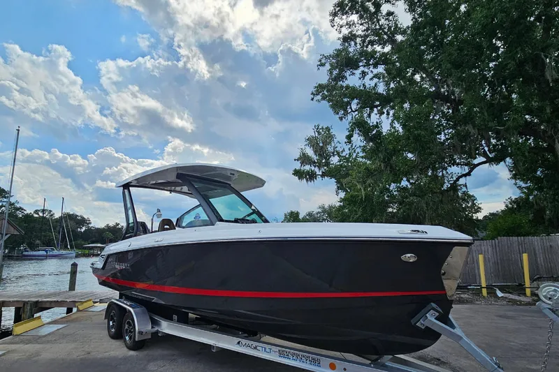Slide: The Image of 2026 Monterey Elite 25 OB boat on trailer, dockside with trees and cloudy sky. - 6