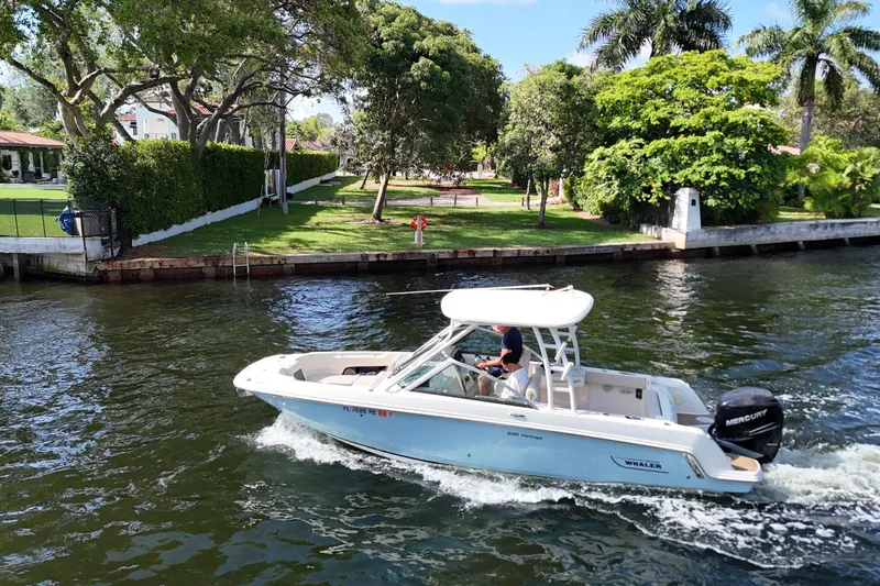 The Image of 2017 Boston Whaler 230 Vantage cruising on a scenic waterway with lush greenery. - 0