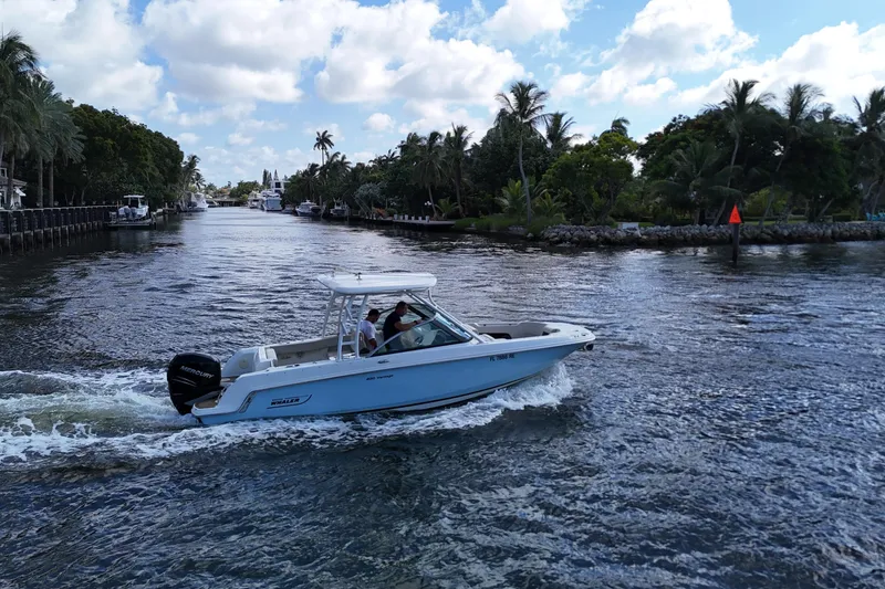 Slide: The Image of 2017 Boston Whaler 230 Vantage cruising on a scenic waterway with palm trees. - 10