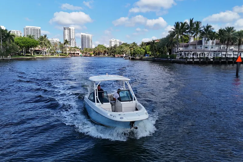 Slide: The Image of 2017 Boston Whaler 230 Vantage cruising on a scenic waterway with city skyline. - 12
