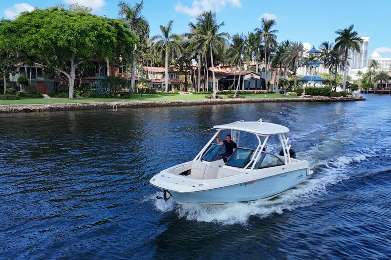 Slide: The Image of 2017 Boston Whaler 230 Vantage cruising on a scenic waterway with palm trees. - 2
