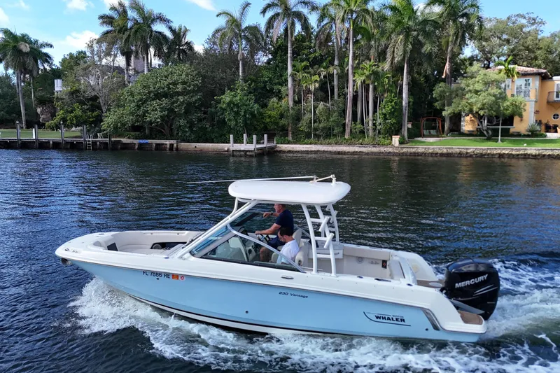 Slide: The Image of 2017 Boston Whaler 230 Vantage cruising on a scenic waterway with lush greenery. - 3