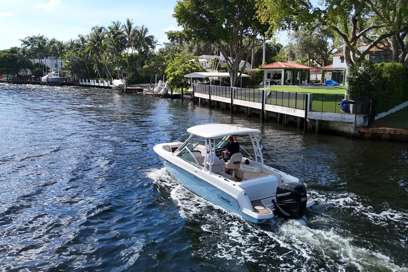 Slide: The Image of 2017 Boston Whaler 230 Vantage cruising on a scenic waterway near luxury homes. - 5