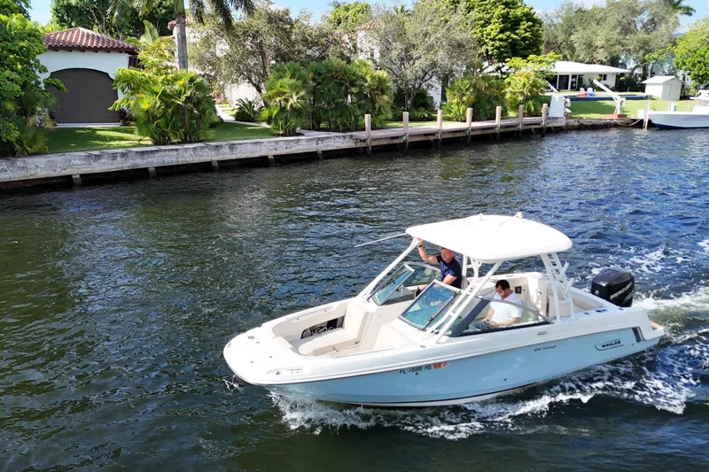 Slide: The Image of 2017 Boston Whaler 230 Vantage cruising on a scenic waterway near lush greenery. - 8