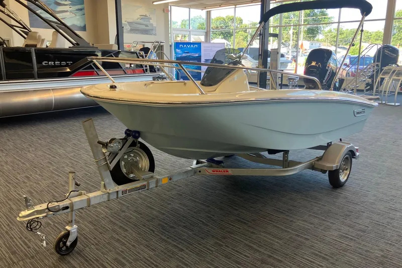 Slide: The Image of 2025 Boston Whaler 130 Super Sport boat on trailer in showroom. - 2