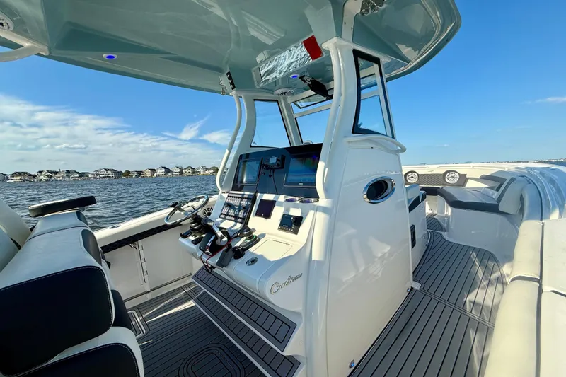 Slide: The Image of 2024 Tidewater 320 CC Adventure boat interior with modern helm and seating, on a sunny day. - 10