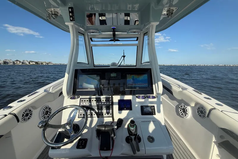 Slide: The Image of 2024 Tidewater 320 CC Adventure boat cockpit with advanced navigation system on open water. - 2