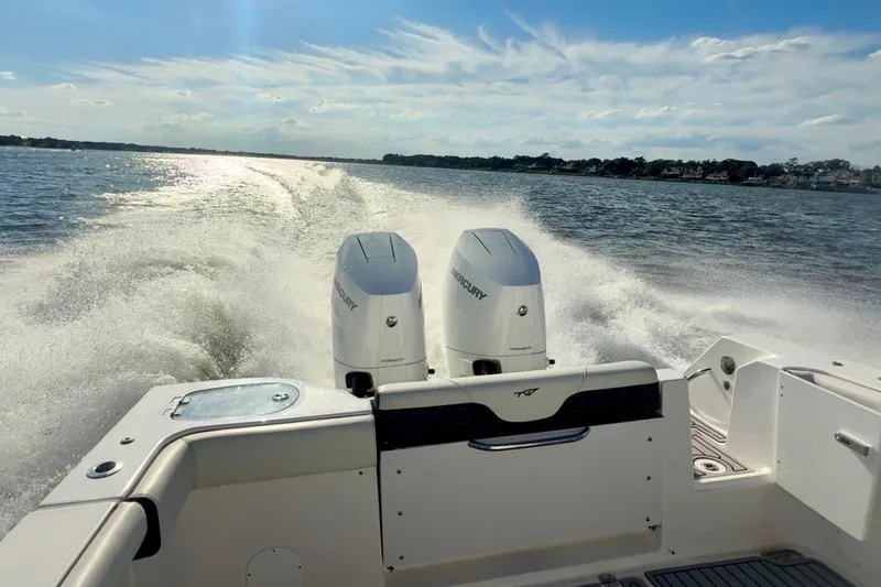 Slide: The Image of 2024 Tidewater 320 CC Adventure boat cruising on open water, twin Mercury engines visible. - 27