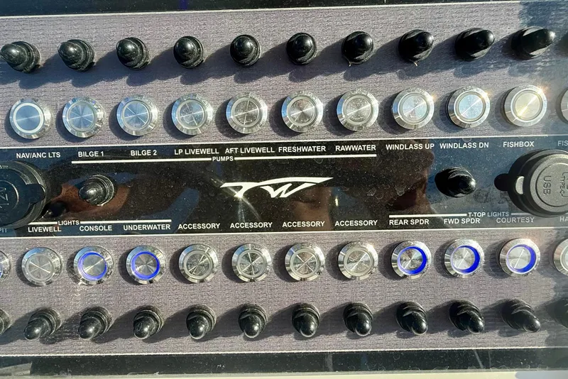 Slide: The Image of Control panel of 2024 Tidewater 320 CC Adventure boat with various switches and buttons. - 28