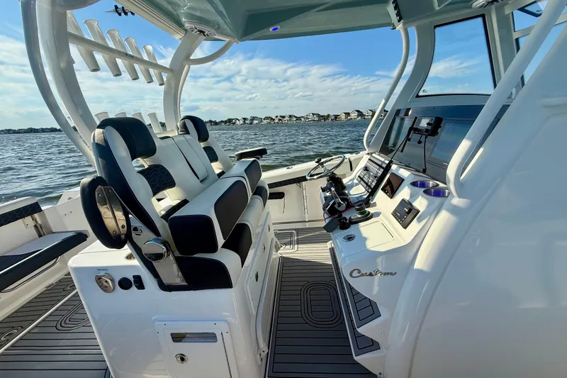 Slide: The Image of 2024 Tidewater 320 CC Adventure boat interior with helm and seating, on a sunny day. - 3