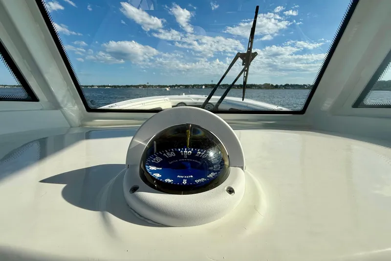 Slide: The Image of 2024 Tidewater 320 CC Adventure boat dashboard with compass, clear sky, and water view. - 31