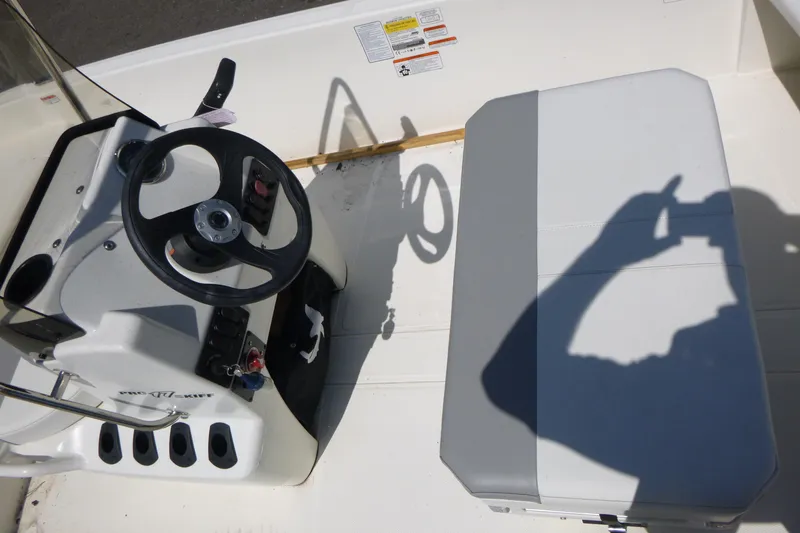 Slide: The Image of 2024 Mako Pro Skiff 17 CC boat interior with steering wheel and seating. - 9