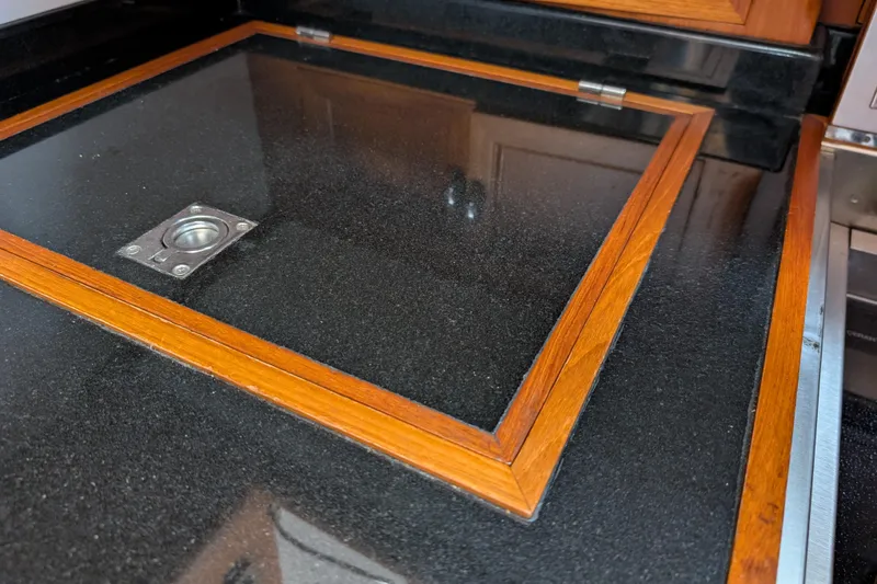 Slide: The Image of 2006 Grand Banks 49 Eastbay SX interior with sleek black countertop and wooden trim. - 49