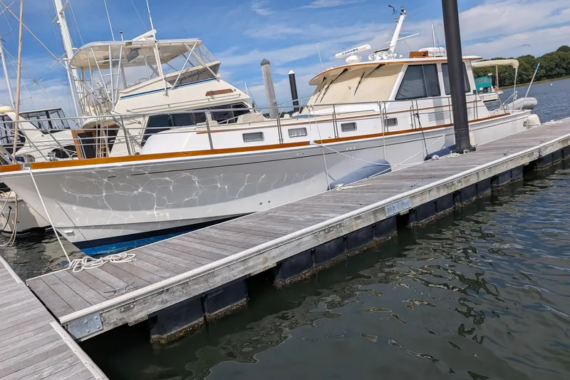 The Image of 2006 Grand Banks 49 Eastbay SX yacht docked at marina under clear blue sky. - 0