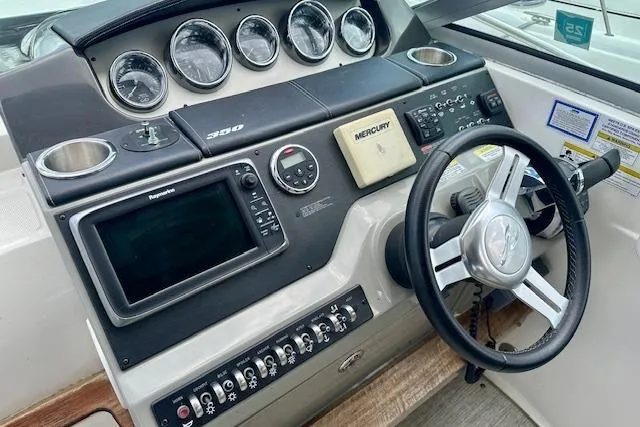 Slide: The Image of 2014 Sea Ray 350 Sundancer helm with gauges, steering wheel, and navigation controls. - 10