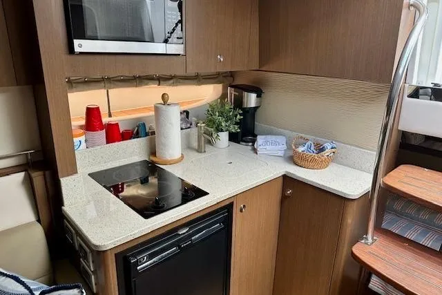 Slide: The Image of 2014 Sea Ray 350 Sundancer galley with modern appliances and wooden cabinetry. - 18