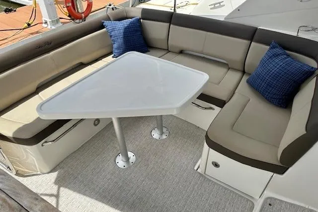 Slide: The Image of 2014 Sea Ray 350 Sundancer boat interior with cushioned seating and table. - 5