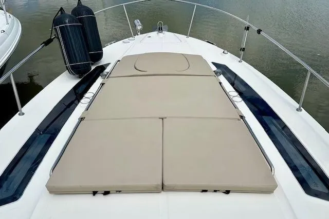 Slide: The Image of 2014 Sea Ray 350 Sundancer boat with cushioned sunbathing deck, docked on calm water. - 8