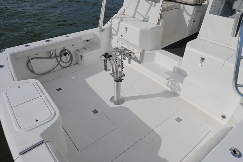 Slide: The Image of 2001 Cabo 35 Express boat deck with fishing rod holder, white seating, and storage compartments. - 18